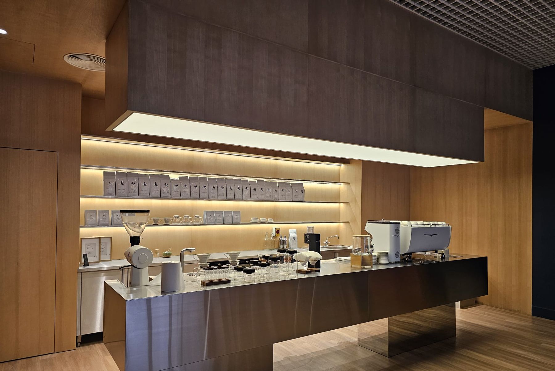 42 Specialty Coffee bar with floating stainless steel counter, backlit oak shelving and suspended light box, fit-out by Interprogetti