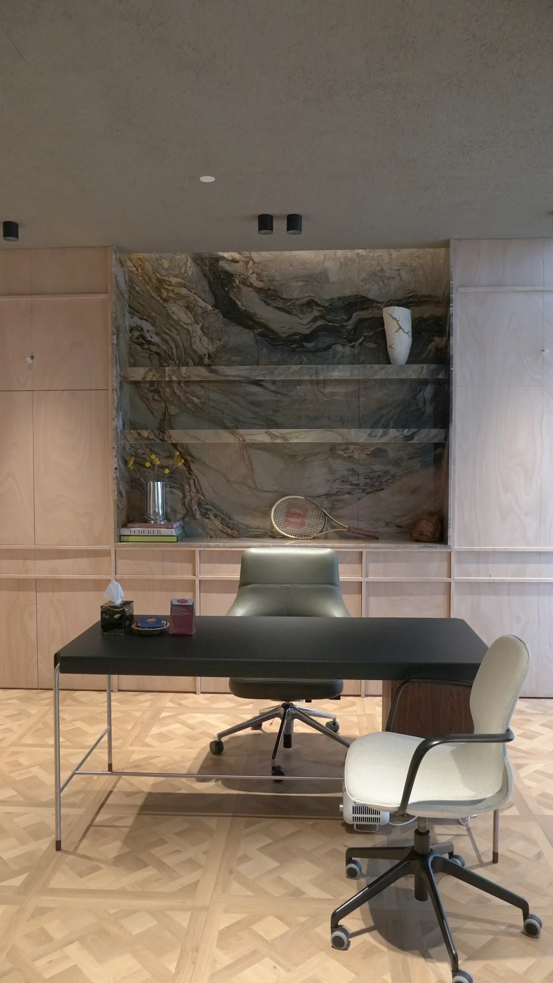 Executive office fit-out at Earth Office, Qatar – quartzite display niche with floating stone shelves, light plywood joinery and black leather desk on Versailles parquet