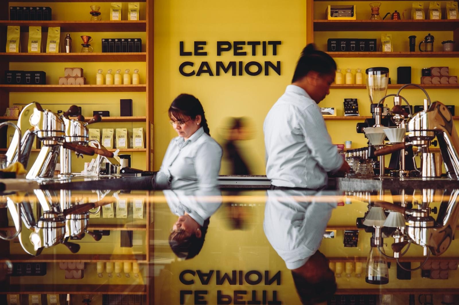 Le Petit Camion specialty coffee bar with yellow feature wall, oak retail shelving and reflective counter, interior fit-out by Interprogetti